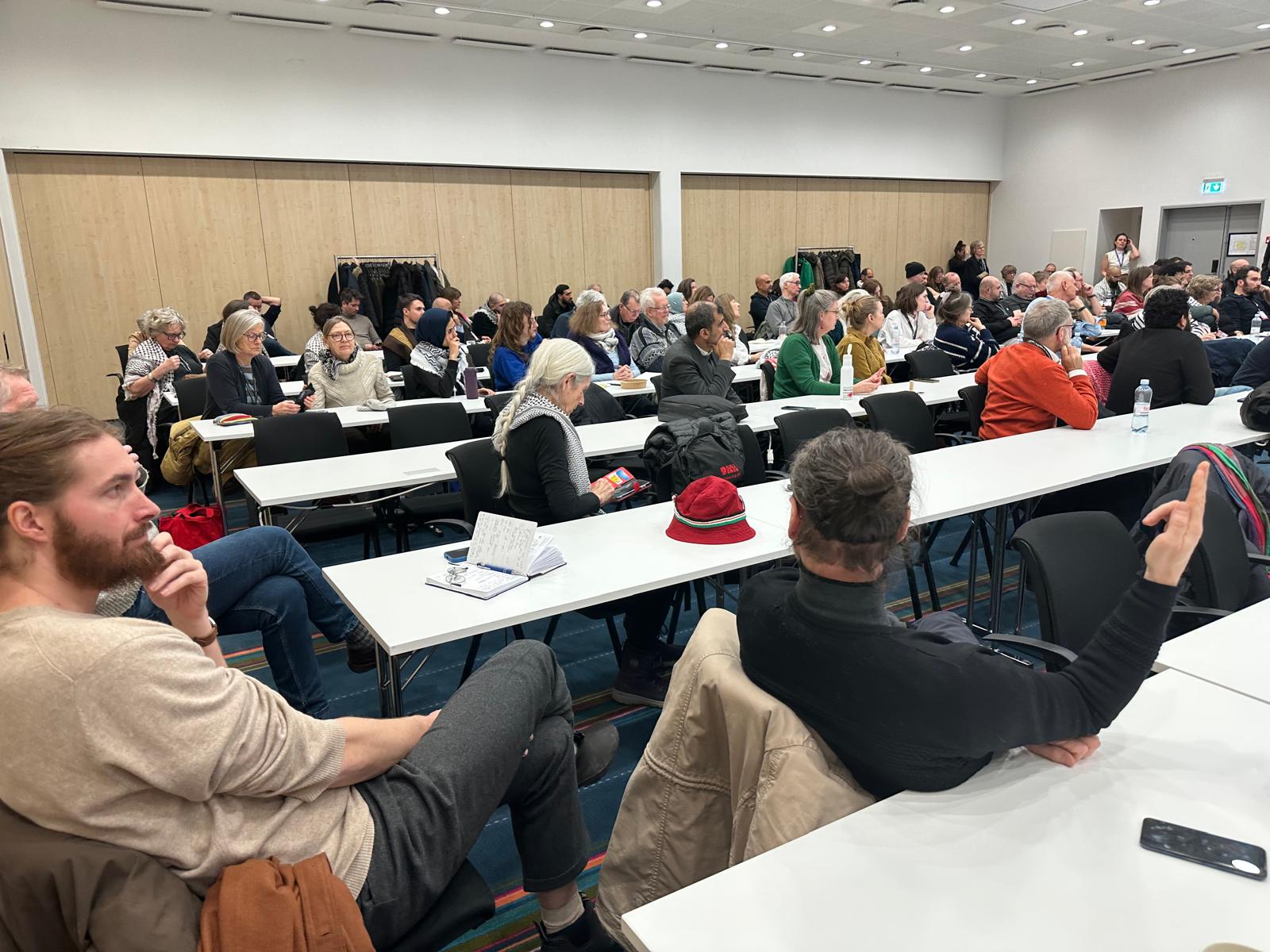 Break-out room with participants at long white tables.