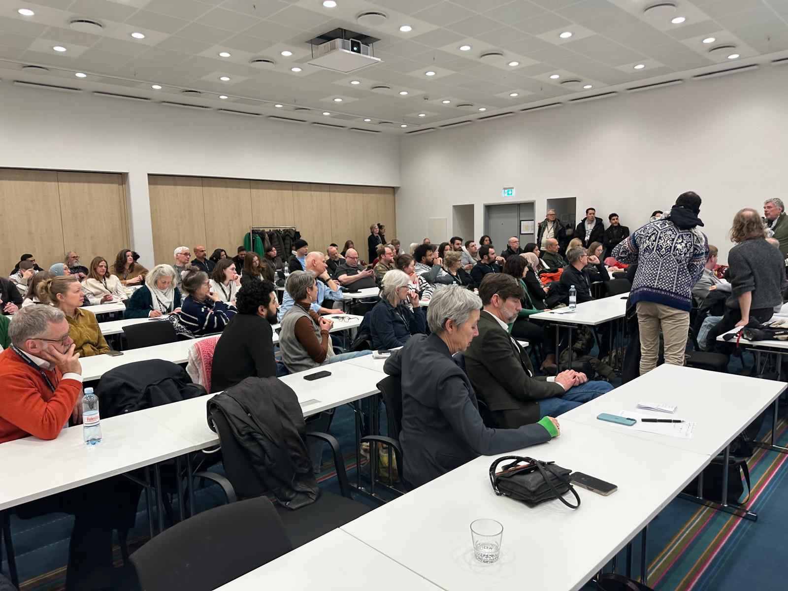 Seminar room with rows of participants at tables.