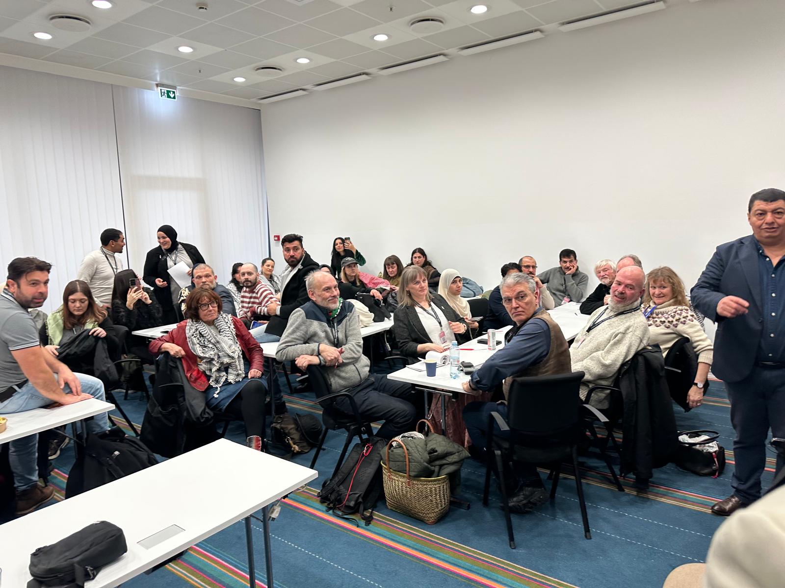 Break-out room with participants at white tables.