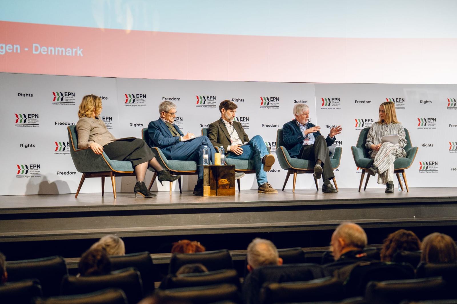 Panel discussion on stage with five panellists in armchairs against the EPN backdrop.