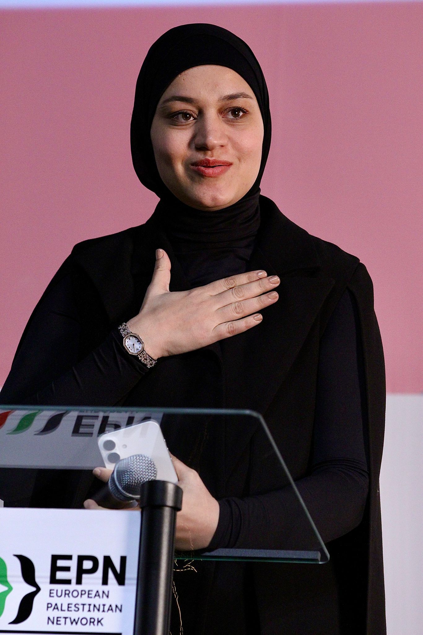 Close-up of a speaker at the lectern with a hand on the heart.